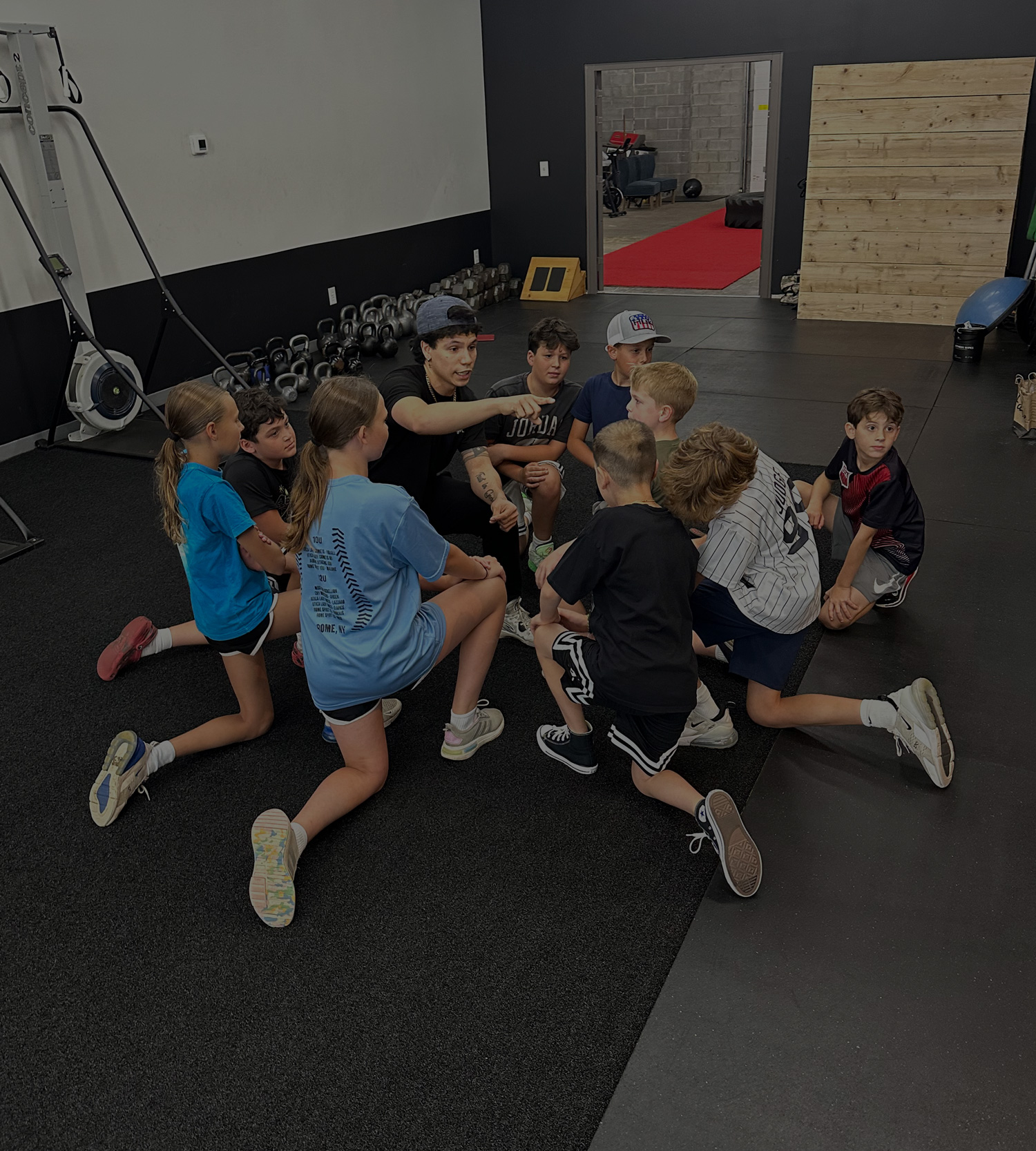 Coach leading a team of young athletes through a warm-up on turf at On The Move Fitness